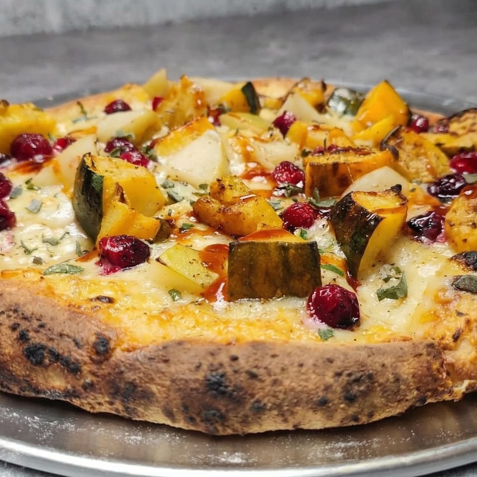 A Fire on the Lake pizza topped with roasted squash, cranberries, and cheese on a metal tray.