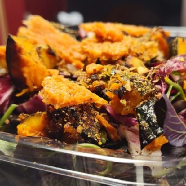Close-up of a Fire on the Lake salad with roasted squash, greens, and crumbled toppings.