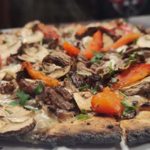 Close-up of a Fire on the Lake pizza with mushrooms, red peppers, and meat.