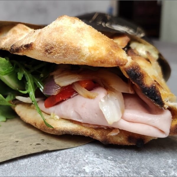 A calzone from Fire on the Lake, filled with ham, roasted peppers, onions, and arugula.