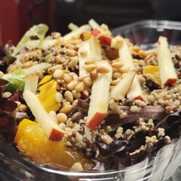A close-up of a Fire on the Lake salad with apples, pine nuts, and yellow fruit.