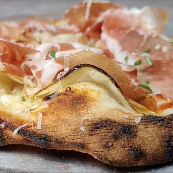 Close-up of a Fire on the Lake pizza with prosciutto, cheese, and a charred crust.